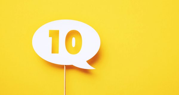 Number 10 written circular white chat bubble sitting on yellow background. Horizontal composition with copy space.
